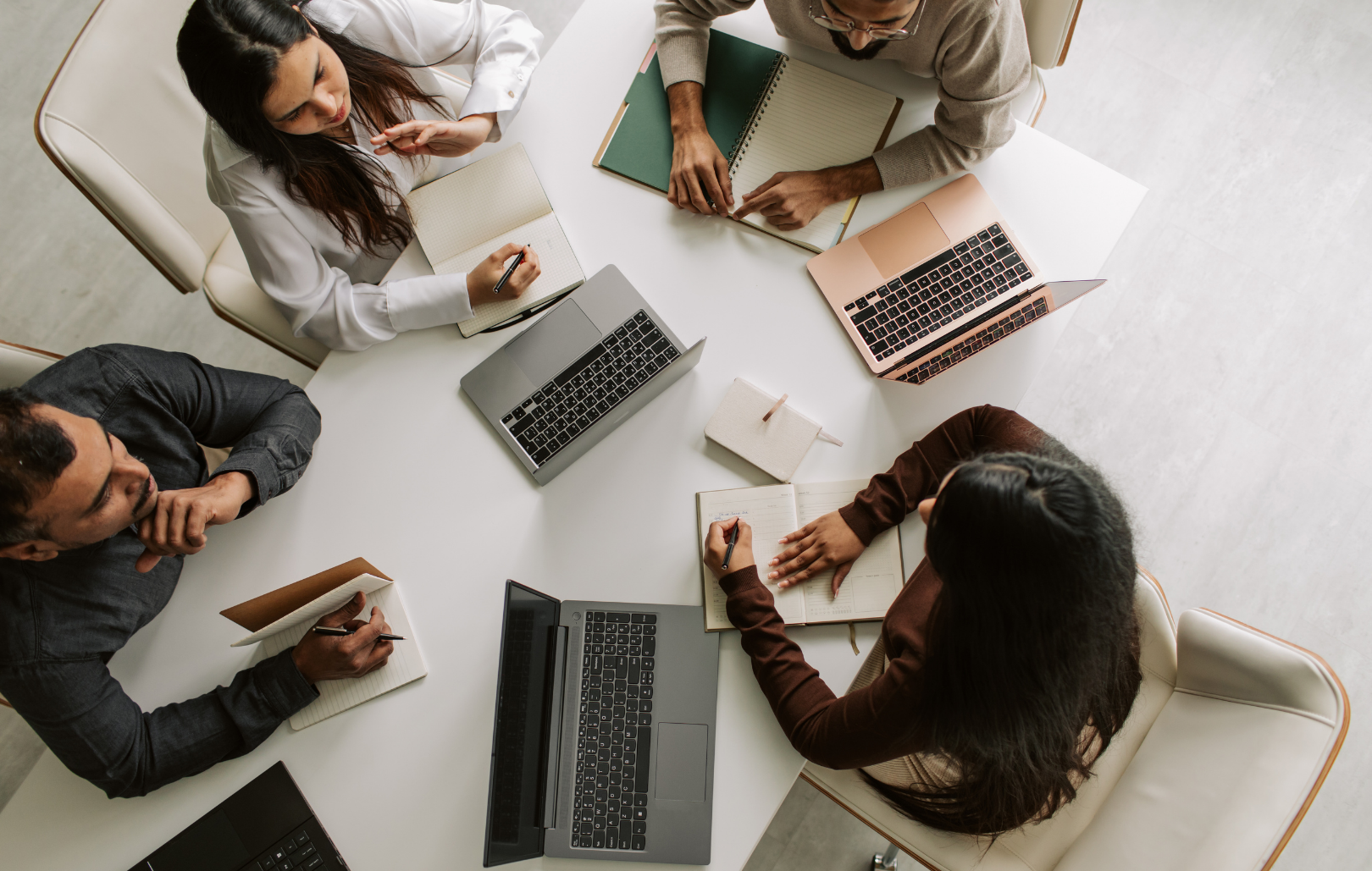 A group of corporate professionals collaborating on a laptop at a table.